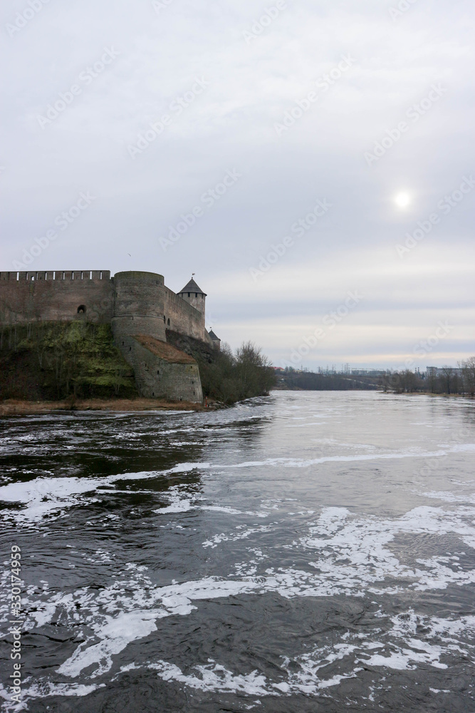 Spring view to Ivangorod fortress on the river Narva with little cold sun in the sky