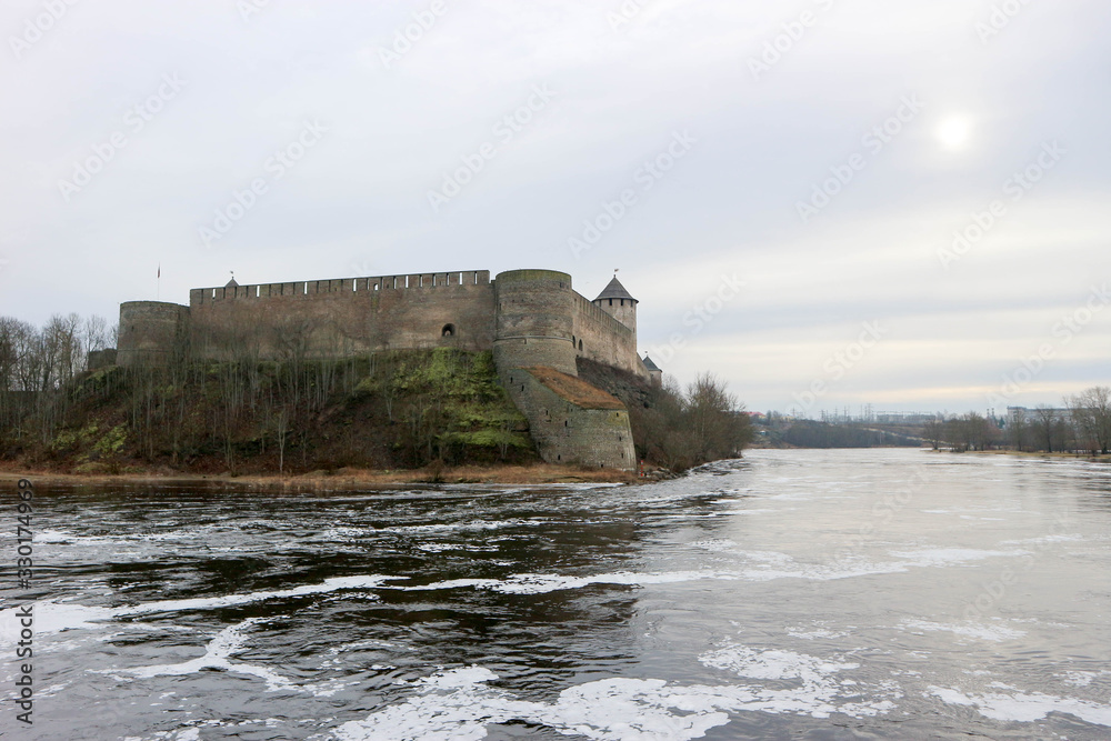 Spring view to Ivangorod fortress on the river Narva with little cold sun in the sky