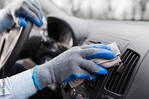 Close up of worker hand cleaning car dashboard.