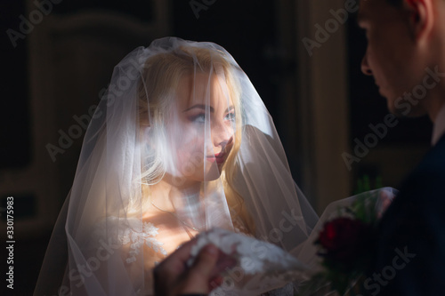 beautiful bride with chic makeup covered with wedding veil and l photo