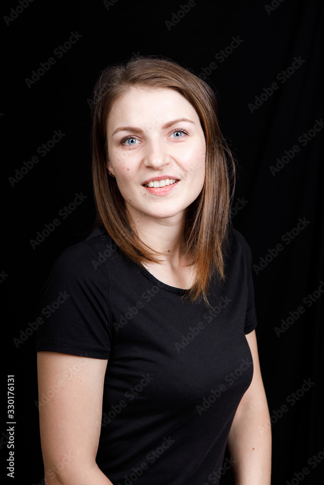 Young woman in a black t-shirt looking directly at the camera on black background Young woman in a black t-shirt looking directly at the camera on black background