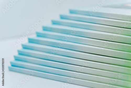 a large stack of blue-green books lies on a white surface. finished products of printed photobooks on a light background