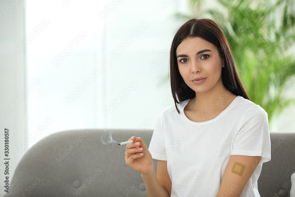 Young woman with nicotine patch and cigarette at home. Space for text Young woman with nicotine patch and cigarette at home. Space for text