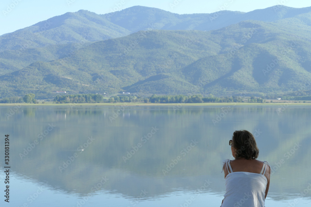 A tourist relaxes while admiring the view of Kerkini lake