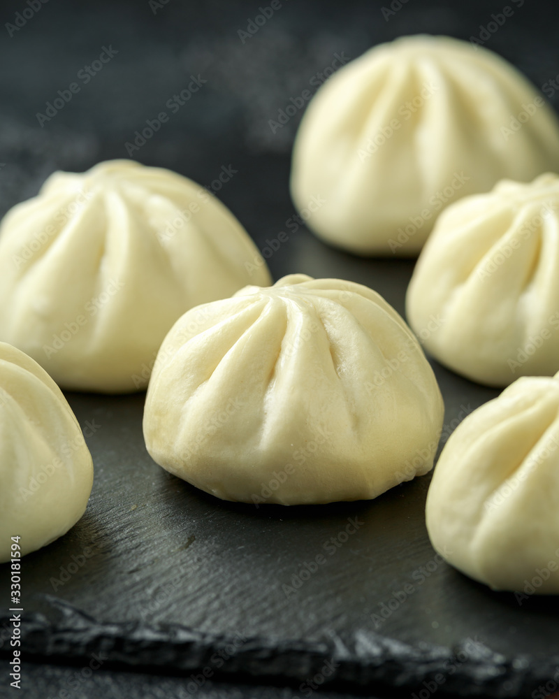 Steamed Buns with duck stuffing, chili sauce on rustic stone board. Asian food