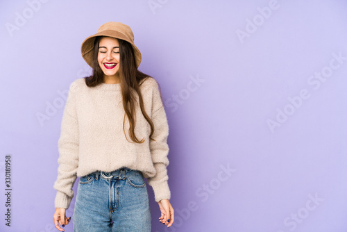 Young caucasian woman isolated on purple background laughs and closes eyes, feels relaxed and happy.
