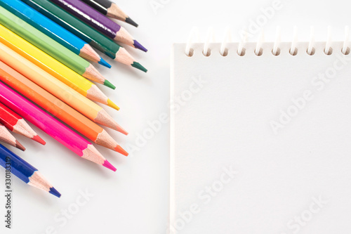 notepad with color pencil on white table view from above