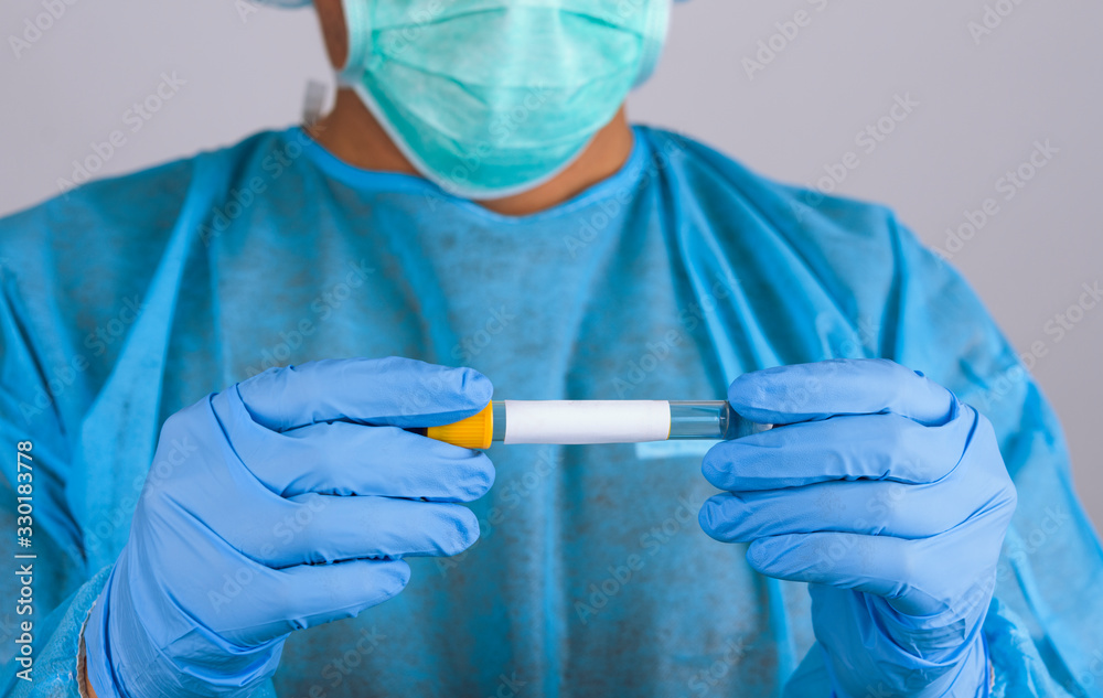 Doctor in blue uniform wearing respirator and latex gloves holds holding test tube with blood for 2019-nCoV analyzing. Coronavirus blood test Concept Doctor in blue uniform wearing respirator and latex gloves holds holding test tube with blood for 2019-nCoV analyzing. Coronavirus blood test Concept