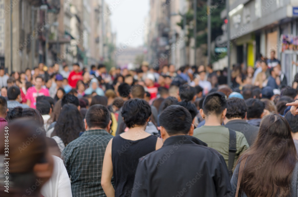 A crowd of crowded people walking side by side as they cross a street