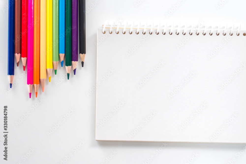 notepad with color pencil on white table view from above notepad with color pencil on white table view from above