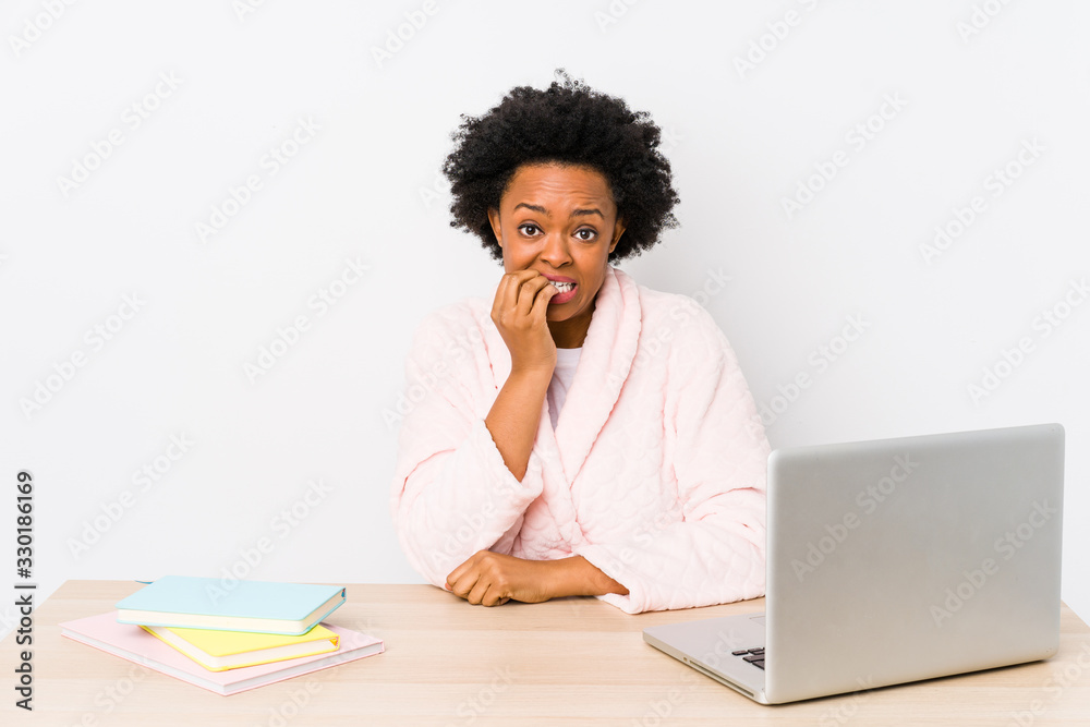Middle aged african american woman working at home isolated biting fingernails, nervous and very anxious.