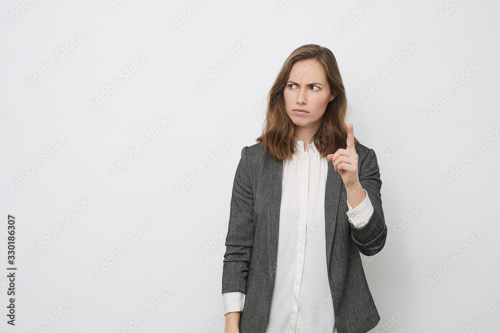 Businesswoman is pointing up while looking mad Businesswoman is pointing up while looking mad