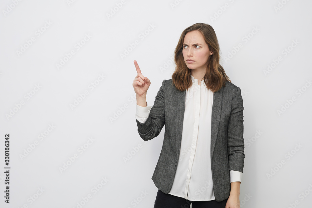 Businesswoman is pointing up while looking mad Businesswoman is pointing up while looking mad