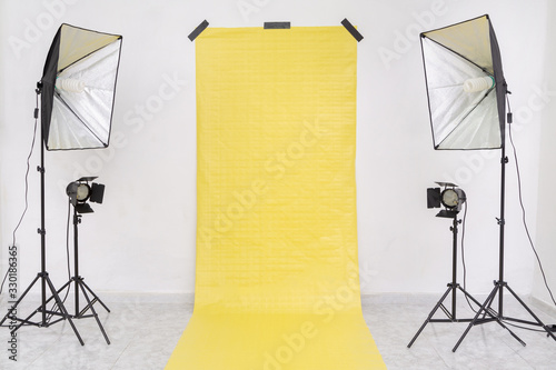 Empty studio with yellow backdrop and light equipment. Copy​ space​ for​ text or​ mock-up