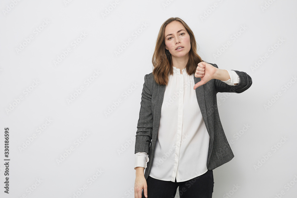 Businesswoman is pointing the thumb down while looking resignedly Businesswoman is pointing the thumb down while looking resignedly