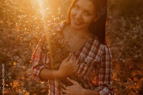 Happy woman with bunch of wildflowers backlit by the sunset light. © mettus