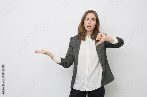 Businesswoman is pointing the thumb down while looking resignedly photo