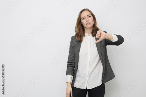Businesswoman is pointing the thumb down while looking resignedly photo