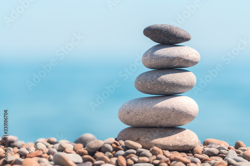 Stack stones on the coast of the sea in the nature. Cairn on the ocean beach  five pebbles tower. Concept of balance and harmony. Calm and spirit