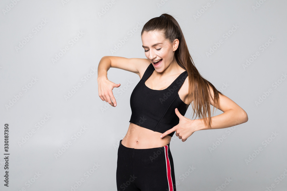 fitness, exercise and diet concept. Portrait of woman pointing finger at her six pack isolated on white background fitness, exercise and diet concept. Portrait of woman pointing finger at her six pack isolated on white background