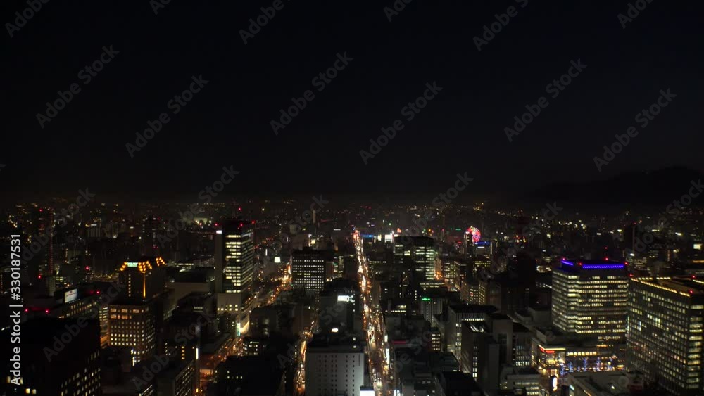 SAPPORO, HOKKAIDO, JAPAN - FEB 2020 : Aerial high angle sunrise view of cityscape of Sapporo city. View of buildings and street traffic around Susukino downtown area. Time lapse shot night to morning. SAPPORO, HOKKAIDO, JAPAN - FEB 2020 : Aerial high angle sunrise view of cityscape of Sapporo city. View of buildings and street traffic around Susukino downtown area. Time lapse shot night to morning.