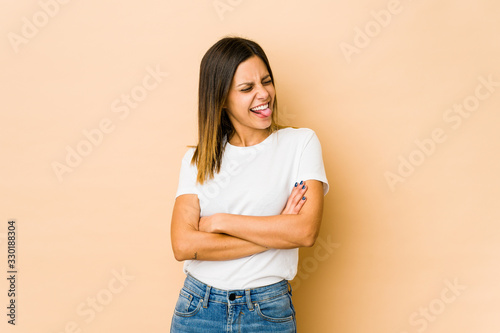 Young woman isolated on beige background funny and friendly sticking out tongue.