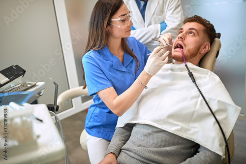 Female dentist repairing tooth to man
