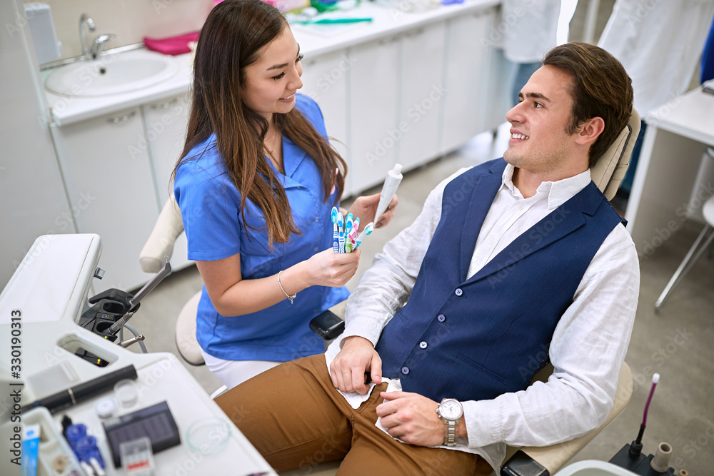 Fototapeta premium Dentist shows to patient toothbrushes and toothpaste
