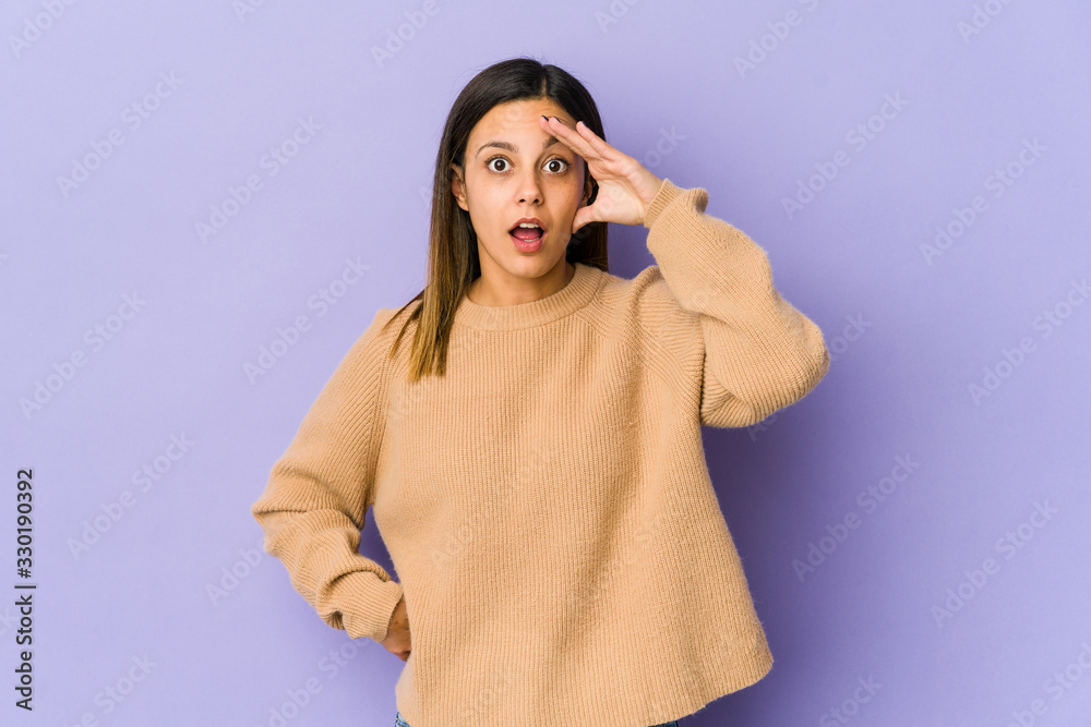 Young woman isolated on purple background looking far away keeping hand on forehead. Young woman isolated on purple background looking far away keeping hand on forehead.
