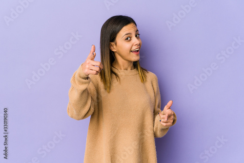 Young woman isolated on purple background pointing to front with fingers.
