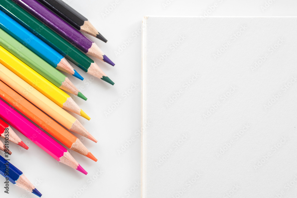 Obraz premium notepad with color pencil on white table view from above
