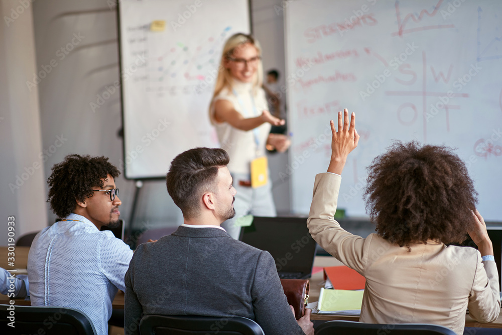 © luckybusiness - Woman asking questions to the speaker during the briefing.