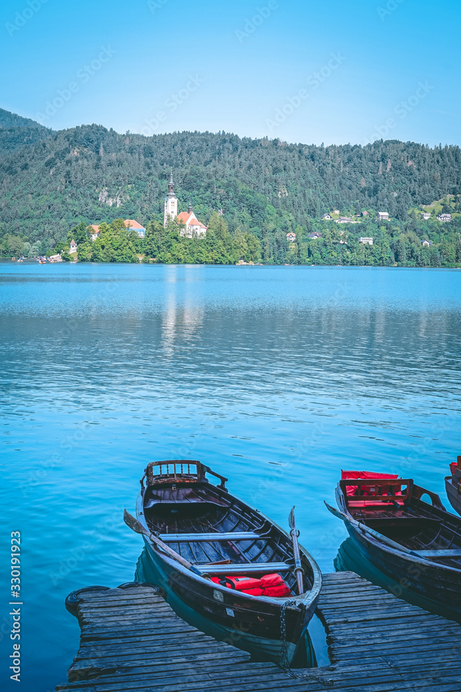 Beautiful view over Bled lake and church in Slovenia and boats at the shore