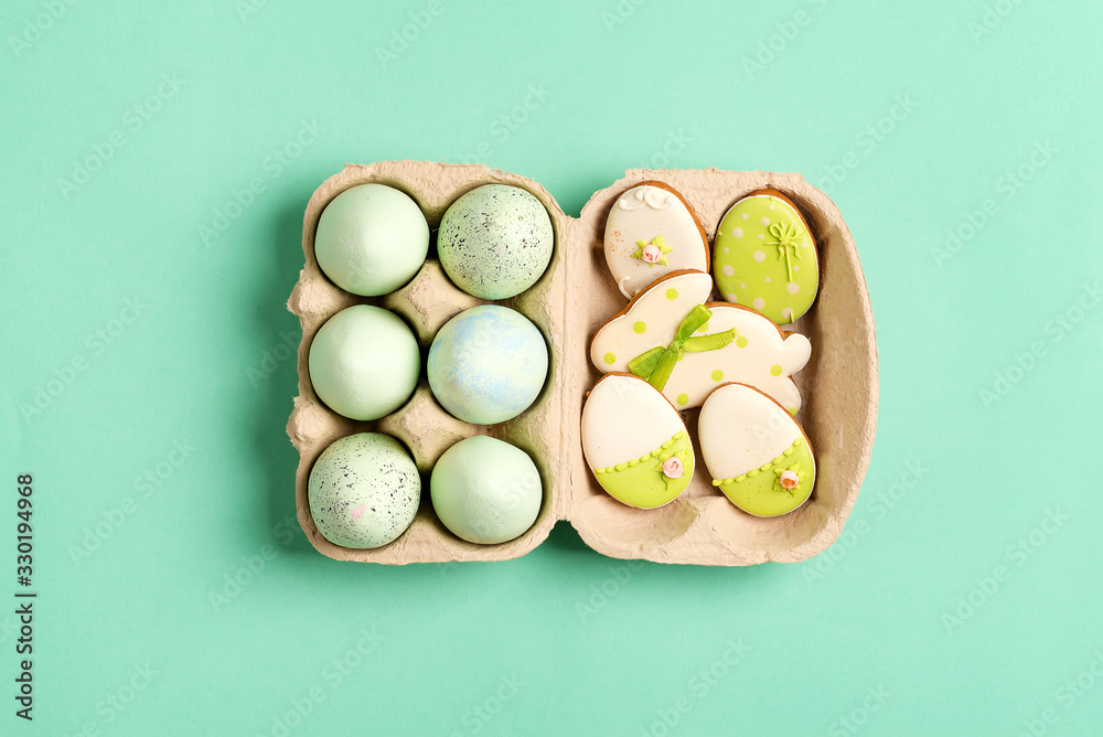 Easter composition from craft painted eggs in paper box and baked cookies on a green background. Easter composition from craft painted eggs in paper box and baked cookies on a green background.