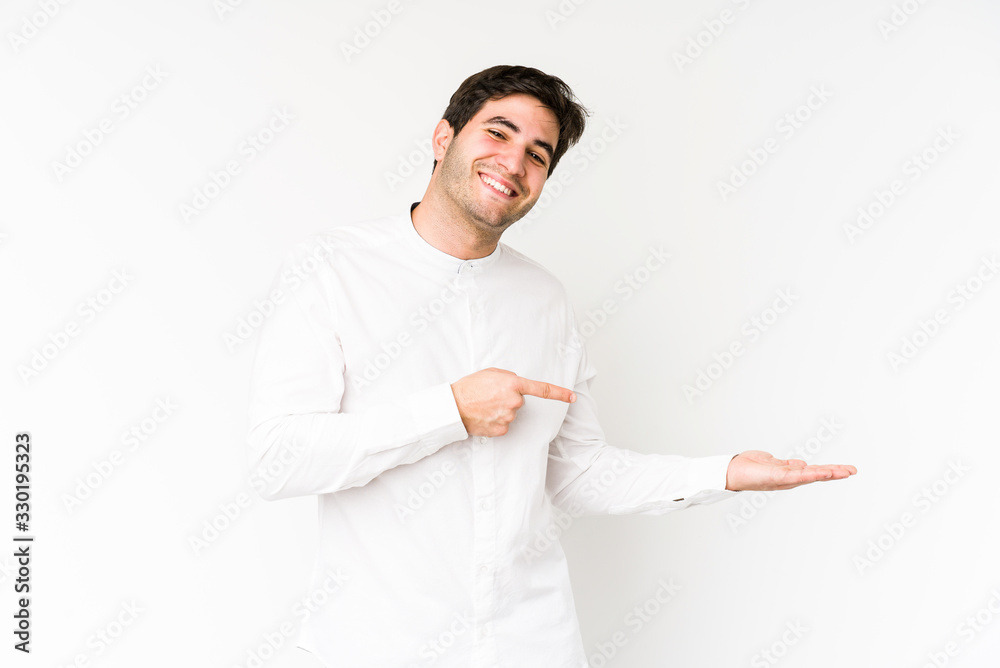 Young man isolated on white background excited holding a copy space on palm. Young man isolated on white background excited holding a copy space on palm.