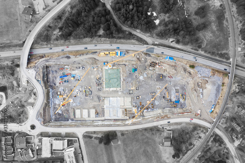 birds eye aerial top view to large construction building site with tower cranes surrounded by streets photo