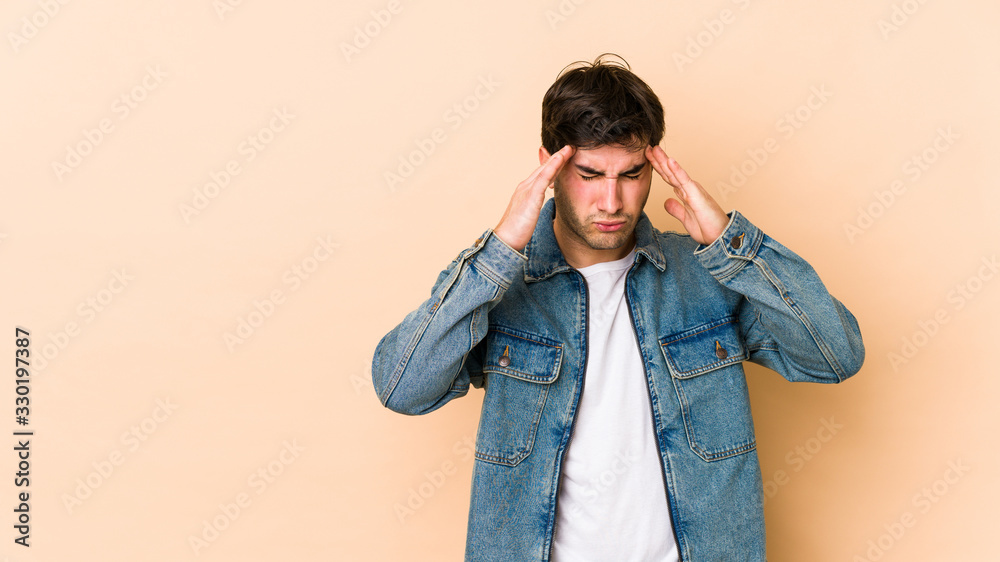 Young man isolated on beige background touching temples and having headache.