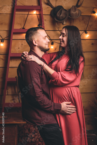 A pregnant girl together with her beloved poses and rejoices in pregnancy. Happy moments