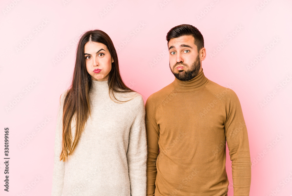 Young caucasian couple isolated blows cheeks, has tired expression. Facial expression concept. Young caucasian couple isolated blows cheeks, has tired expression. Facial expression concept.