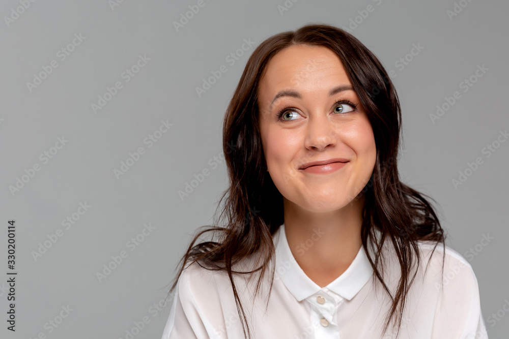 Smiling young business woman in white shirt posing isolated on grey wall background studio portrait. Achievement career wealth business concept. Mock up copy space.