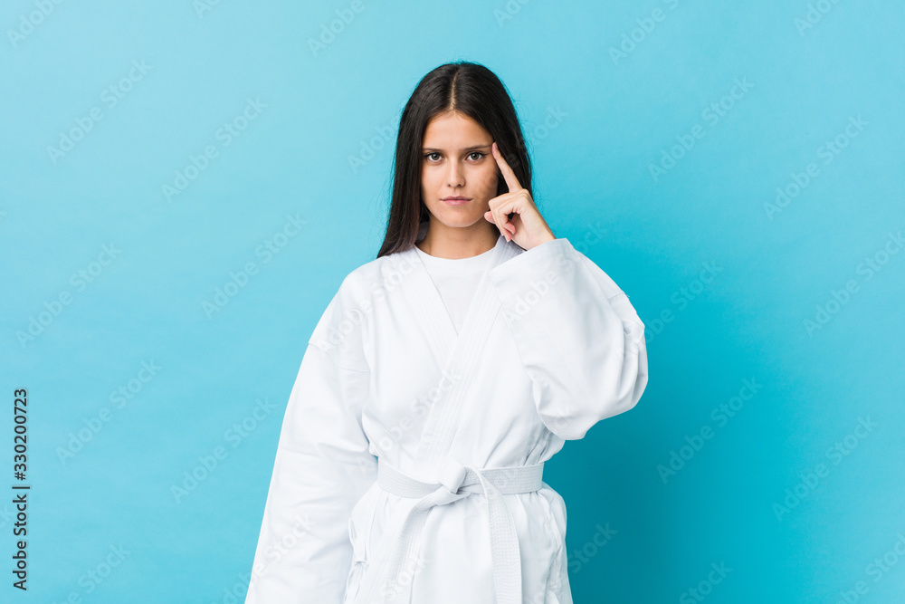 Young karate woman pointing his temple with finger, thinking, focused on a task. Young karate woman pointing his temple with finger, thinking, focused on a task.