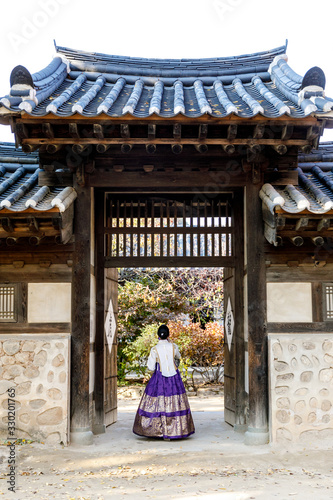 Seoul, South Korea- 30th Oct 2018- A woman wearing Hanbok walks through a traditional gate at the Korean Folk Village