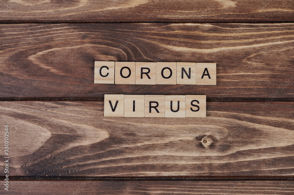 the word Coronavirus, laid with wooden capital letters on wooden background