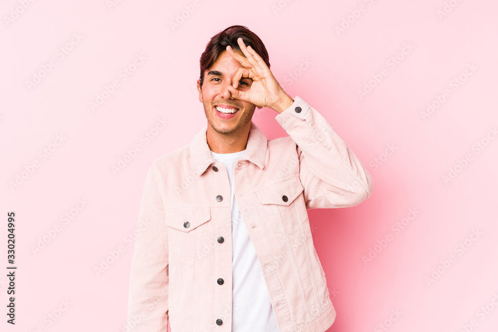 Young caucasian man posing in a pink background isolated excited keeping ok gesture on eye. Young caucasian man posing in a pink background isolated excited keeping ok gesture on eye.