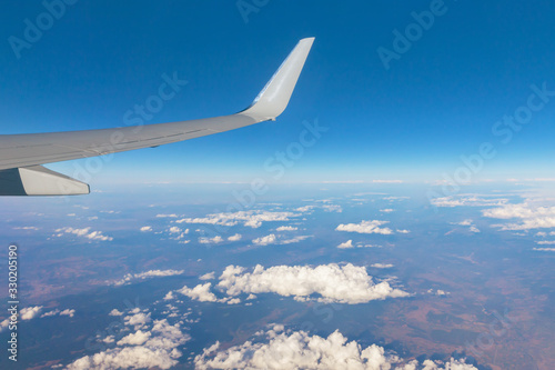Wing of an airplane against a blue sky and white clouds in a blur.Selective focus.Concept of scenery journey flying.