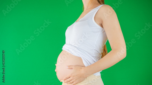 Young pregnant woman's belly close up with her hands on her tummy stroking the baby. Beautiful background photo of pregnancy and maternity photo