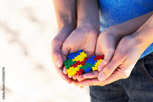 World autism awareness day concept. Child and adult hands holding colorful heart together © vejaa
