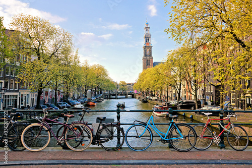 Bicycles lining a bridge over the canals of Amsterdam with church in background. Late day light. Netherlands.