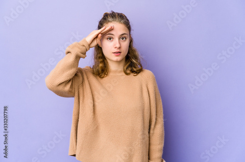 Young caucasian woman on purple background shouts loud, keeps eyes opened and hands tense.