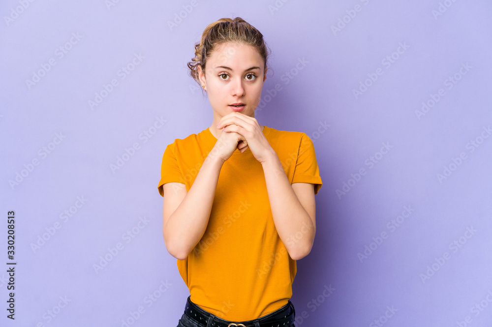 Young caucasian woman on purple background praying for luck, amazed and opening mouth looking to front. Young caucasian woman on purple background praying for luck, amazed and opening mouth looking to front.